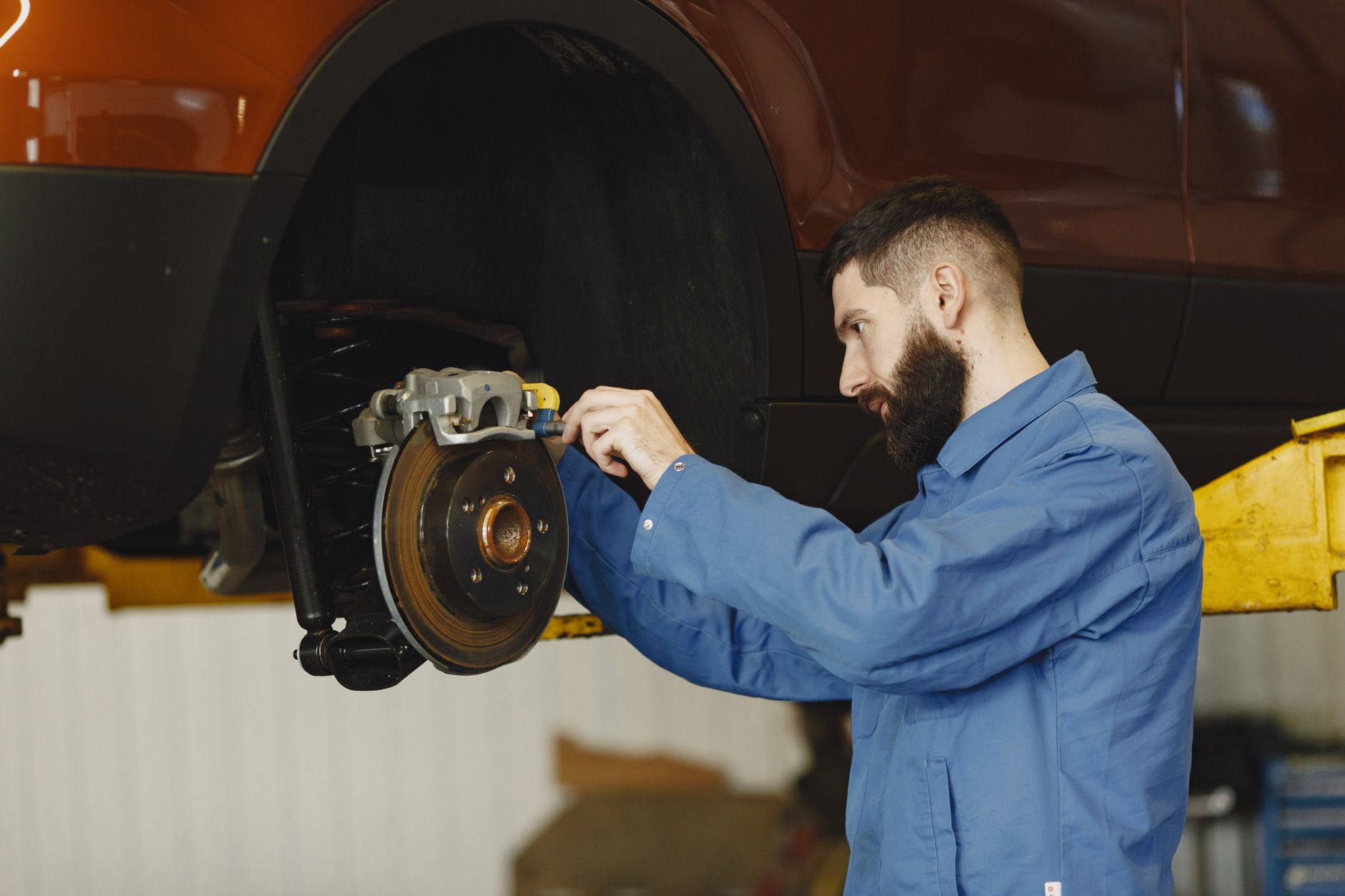 Mechanic performing a brake repair on a car in a modern garage